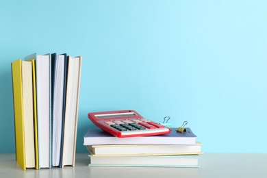 Hardcover books and calculator on table against color background, space for text