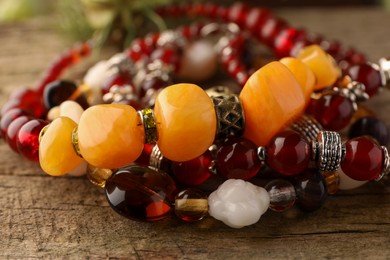 Beautiful bracelets with gemstones on wooden surface, closeup