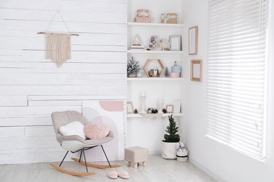 Stylish room interior with rocking chair, wall shelves and beautiful Christmas decor