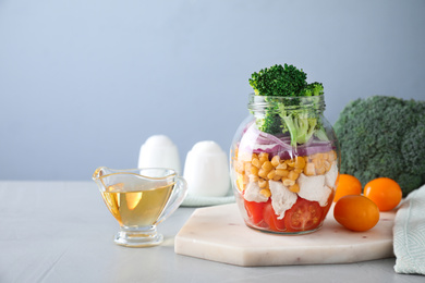 Photo of Healthy salad in glass jar on light grey table