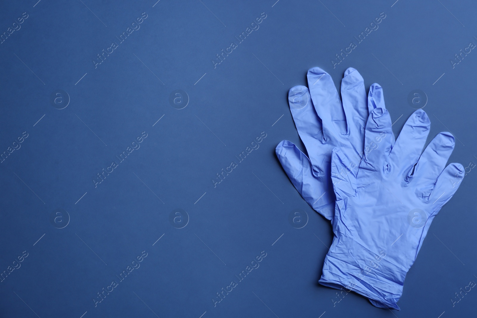 Photo of Pair of medical gloves on blue background, flat lay. Space for text