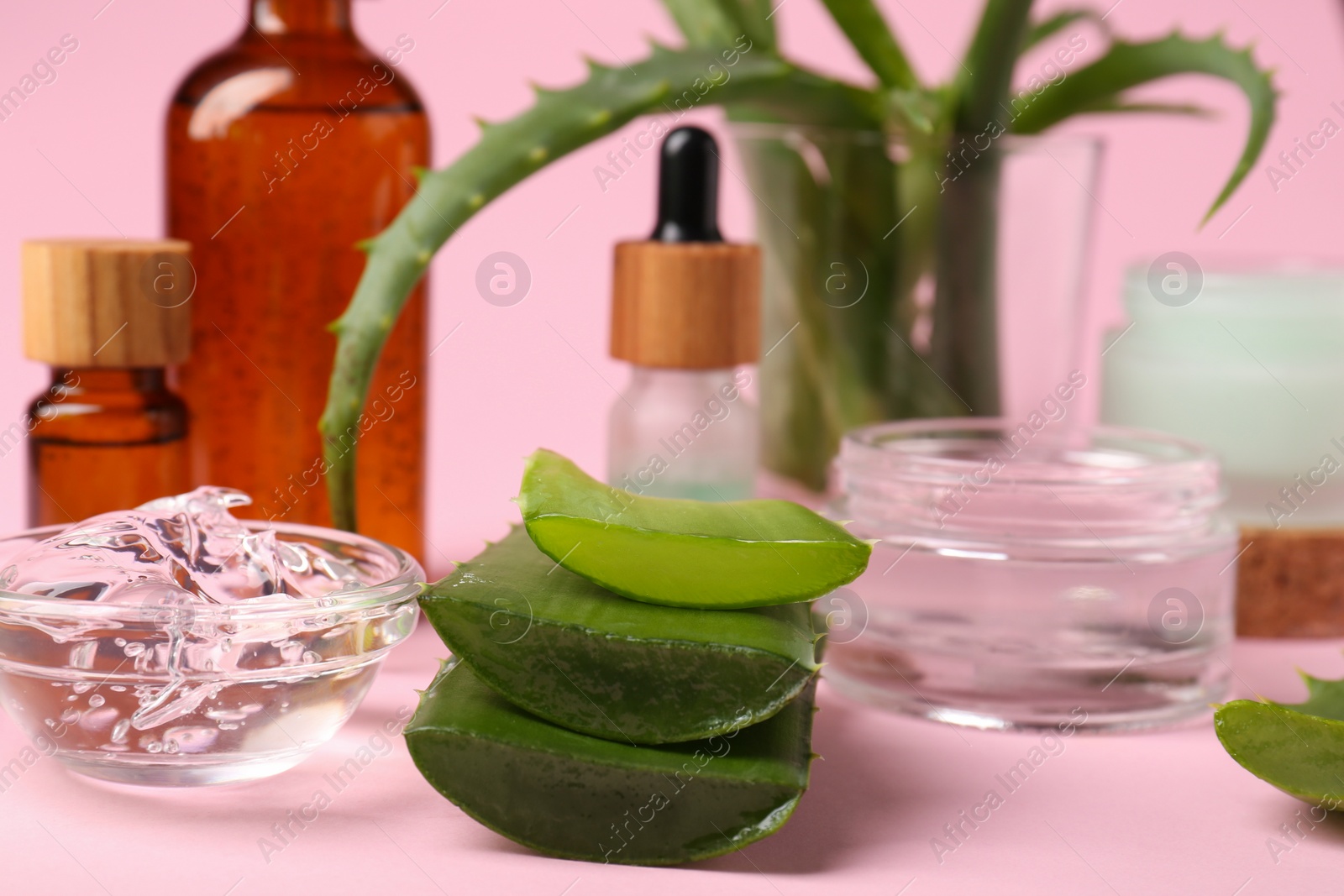 Photo of Cut aloe and natural gel on pink background, closeup