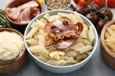 Tasty pasta with bacon and cheese on grey table