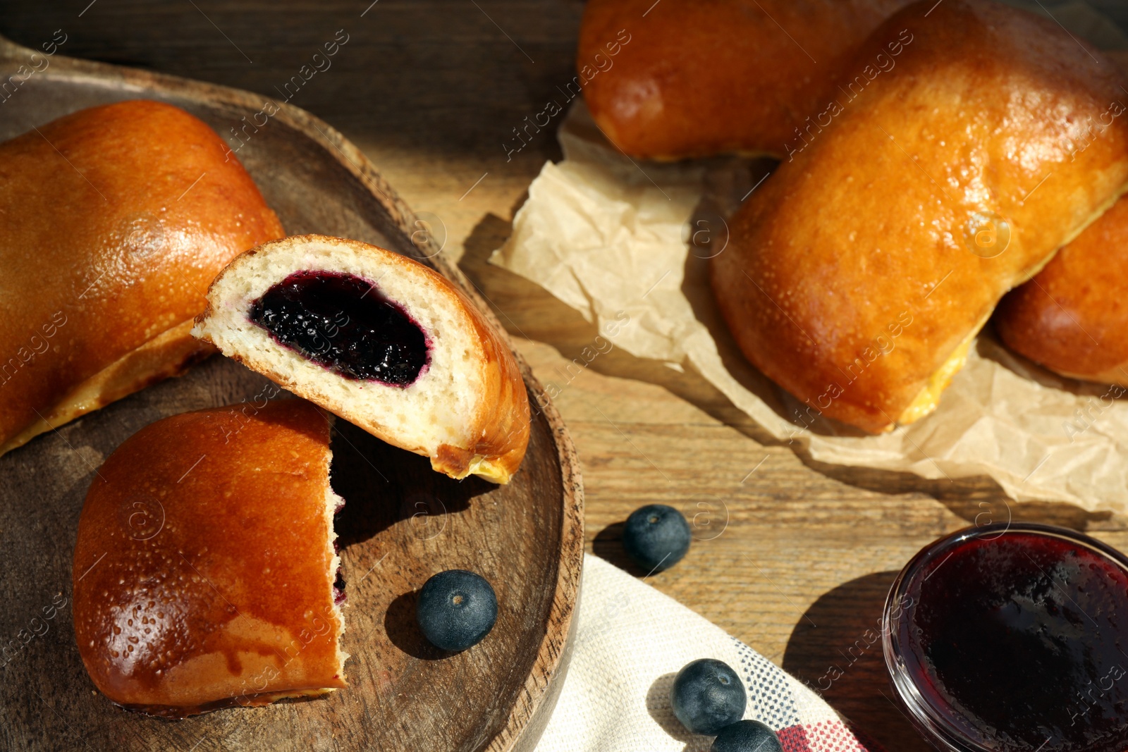 Photo of Delicious baked patties with jam and blueberries on wooden table, above view