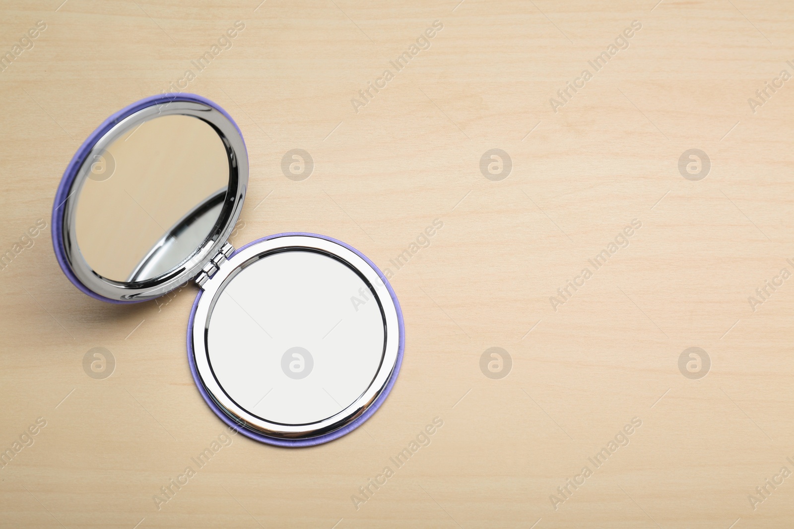 Photo of Stylish cosmetic pocket mirror on wooden table, top view. Space for text