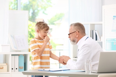 Coughing little boy visiting doctor at clinic