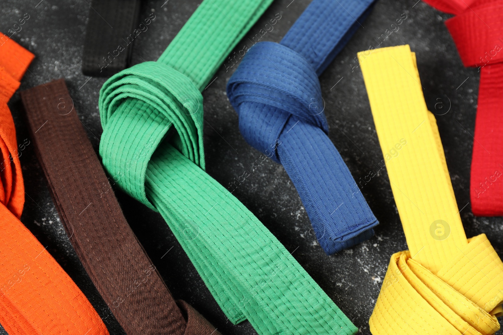 Photo of Colorful karate belts on gray background, closeup