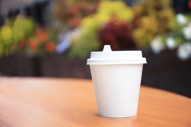 Cardboard cup with tasty coffee on table outdoors