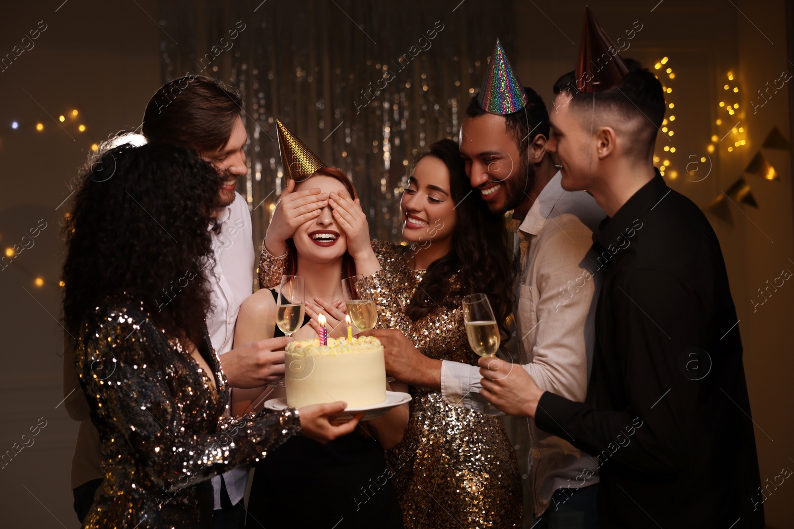 Photo of Happy friends with tasty cake and glasses of sparkling wine celebrating birthday indoors