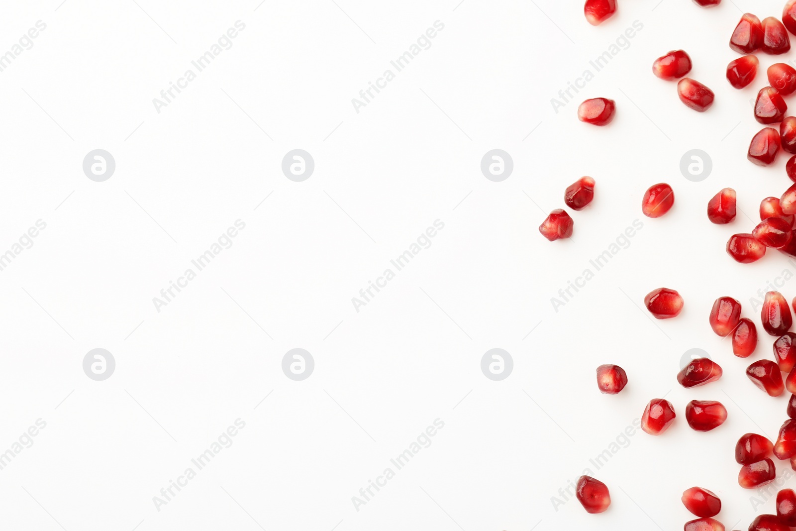 Photo of Many ripe juicy pomegranate grains on white background, flat lay. Space for text