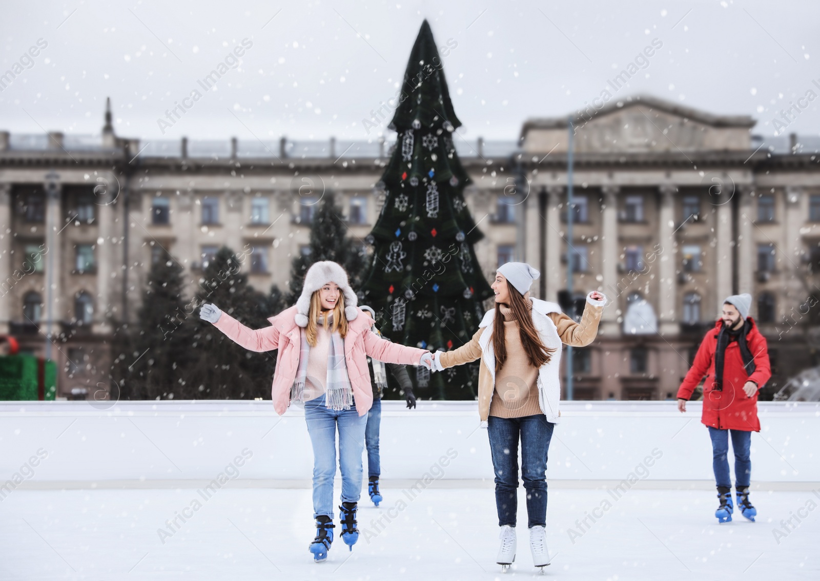 Image of Happy friends skating along ice rink outdoors