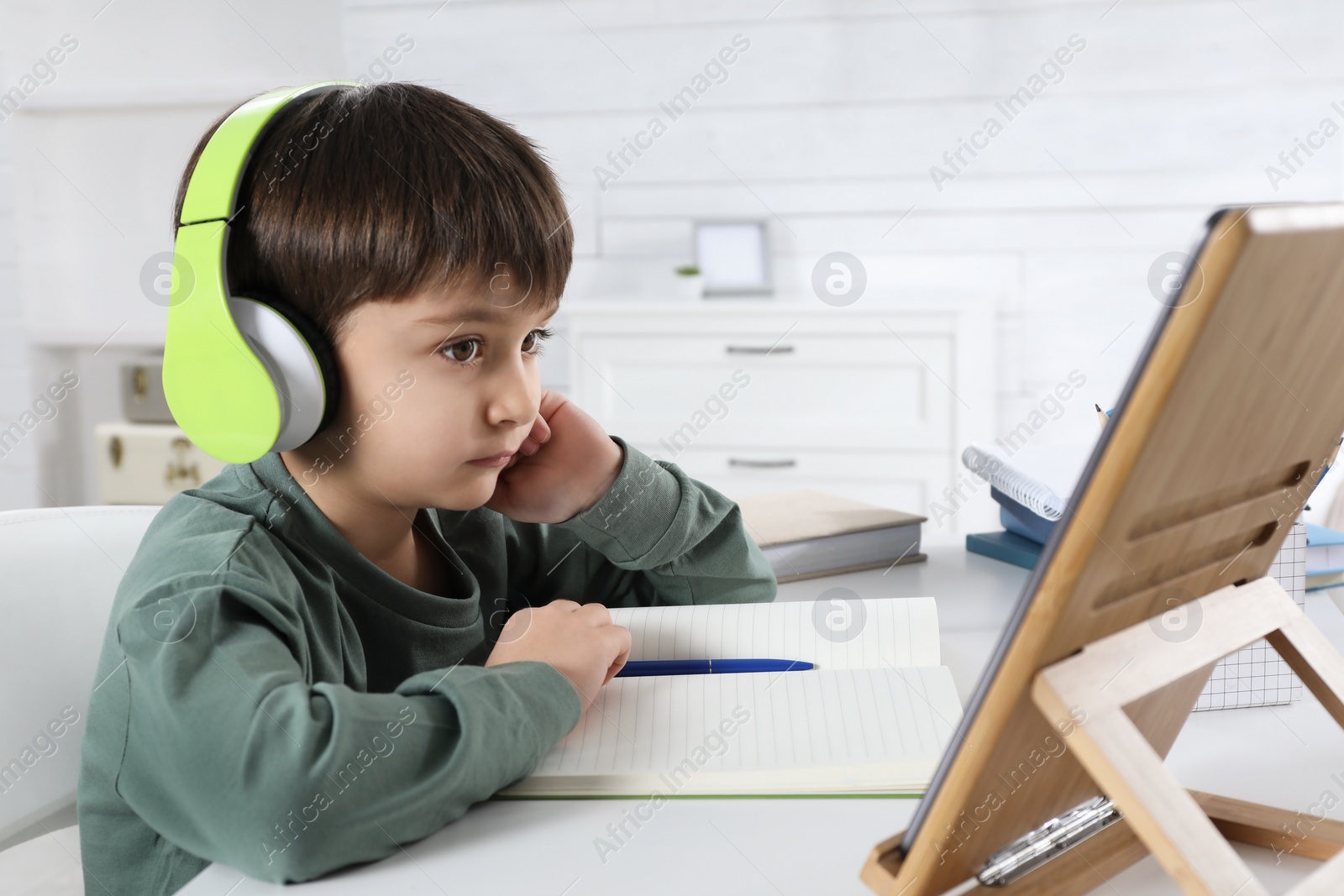 Photo of Cute little boy with modern tablet studying online at home. E-learning