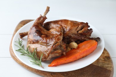 Photo of Tasty cooked rabbit meat with rosemary, garlic and carrot on white table, closeup
