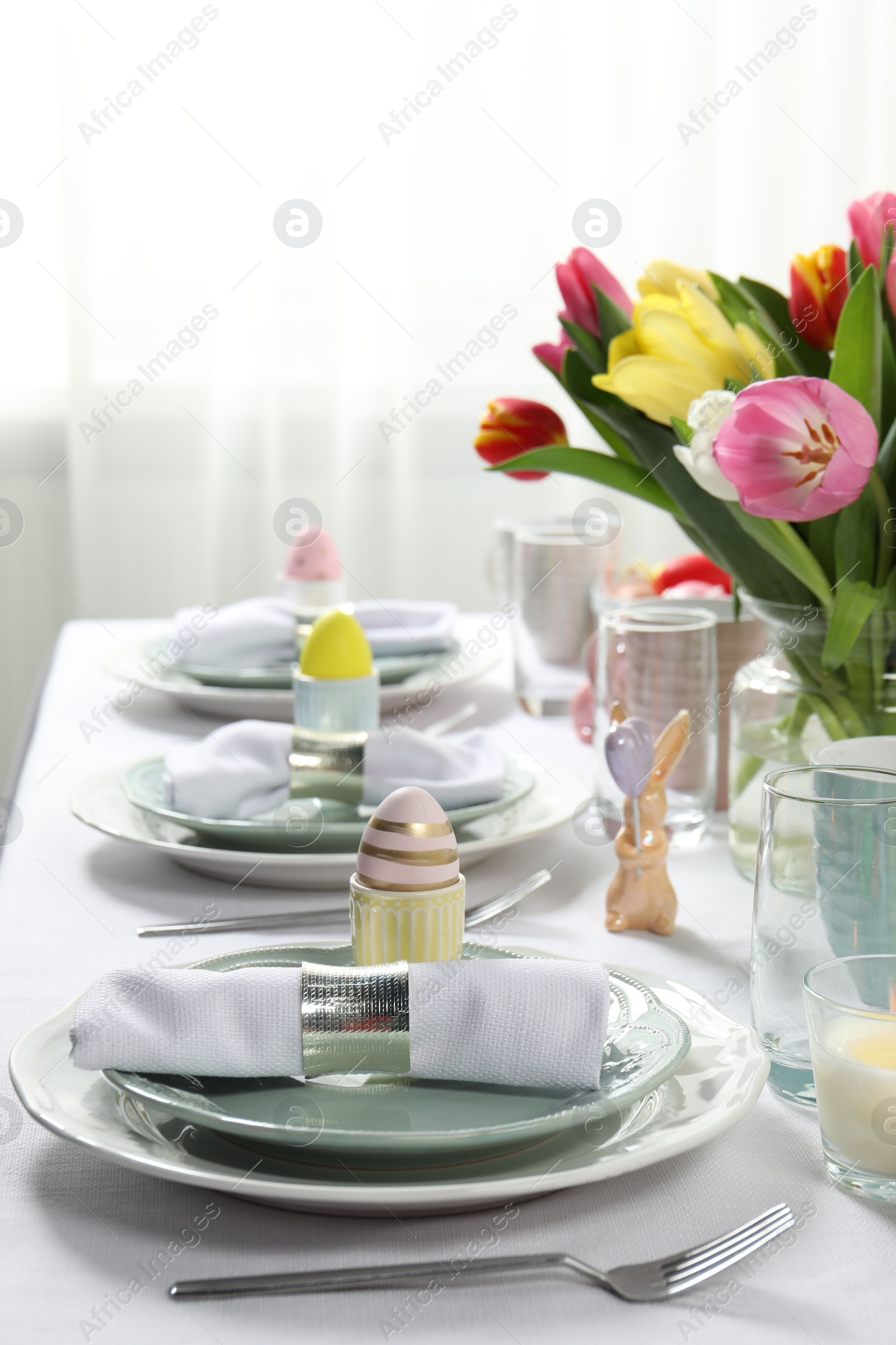 Photo of Easter celebration. Festive table setting with beautiful flowers and painted eggs