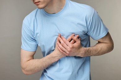 Man suffering from heart hurt on grey background, closeup
