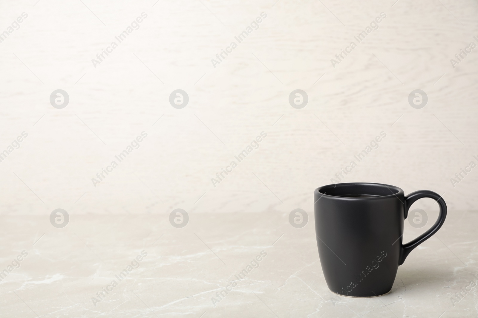 Photo of Black ceramic cup with hot aromatic coffee on table