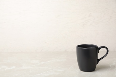 Black ceramic cup with hot aromatic coffee on table