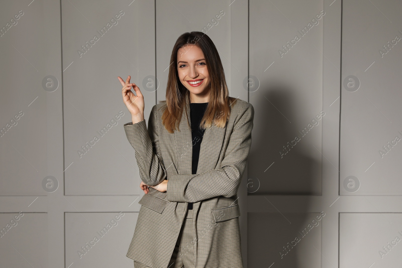 Photo of Portrait of beautiful young woman in fashionable suit near light grey wall. Business attire