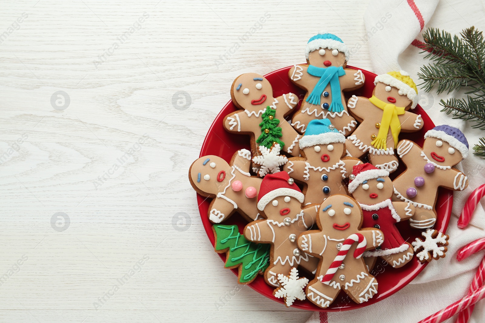 Photo of Delicious Christmas cookies, candies and fir branches on white wooden table, flat lay. Space for text