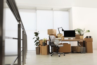 Photo of Cardboard boxes, computer and furniture in new office. Moving day