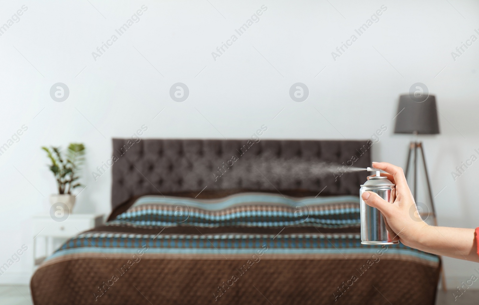 Photo of Woman spraying air freshener in bedroom