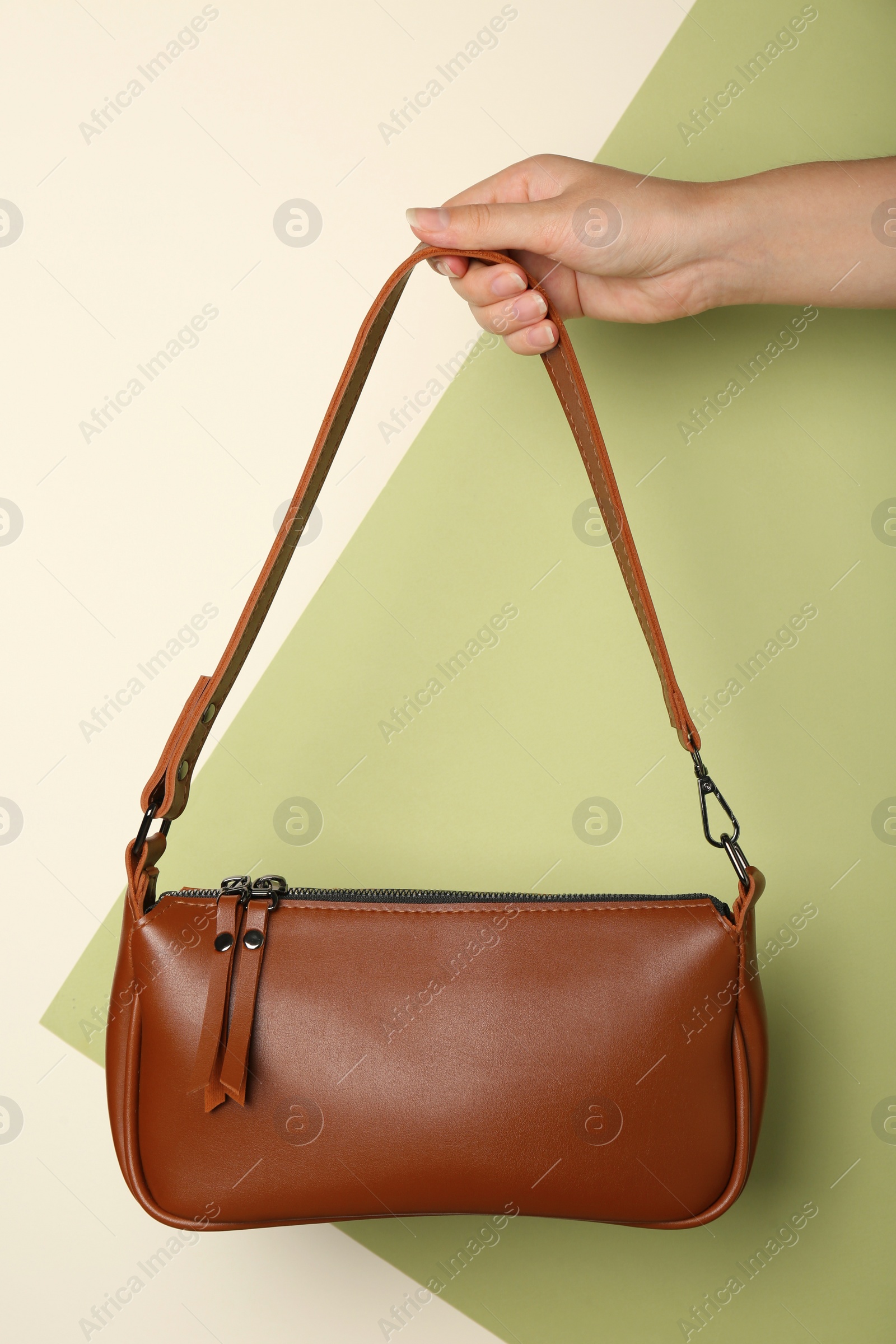 Photo of Woman holding stylish brown bag on color background, closeup