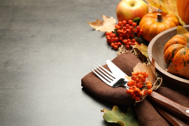 Photo of Closeup view of seasonal table setting with autumn leaves, pumpkins and ashberries on grey background, space for text. Thanksgiving Day
