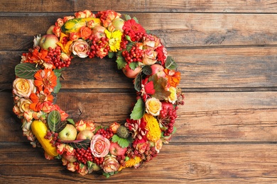 Photo of Beautiful autumnal wreath with flowers, berries and fruits on wooden background, top view. Space for text