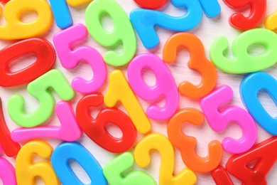 Photo of Colorful numbers on white wooden school desk, top view