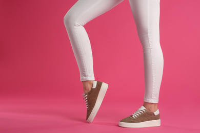 Woman wearing shoes on pink background, closeup