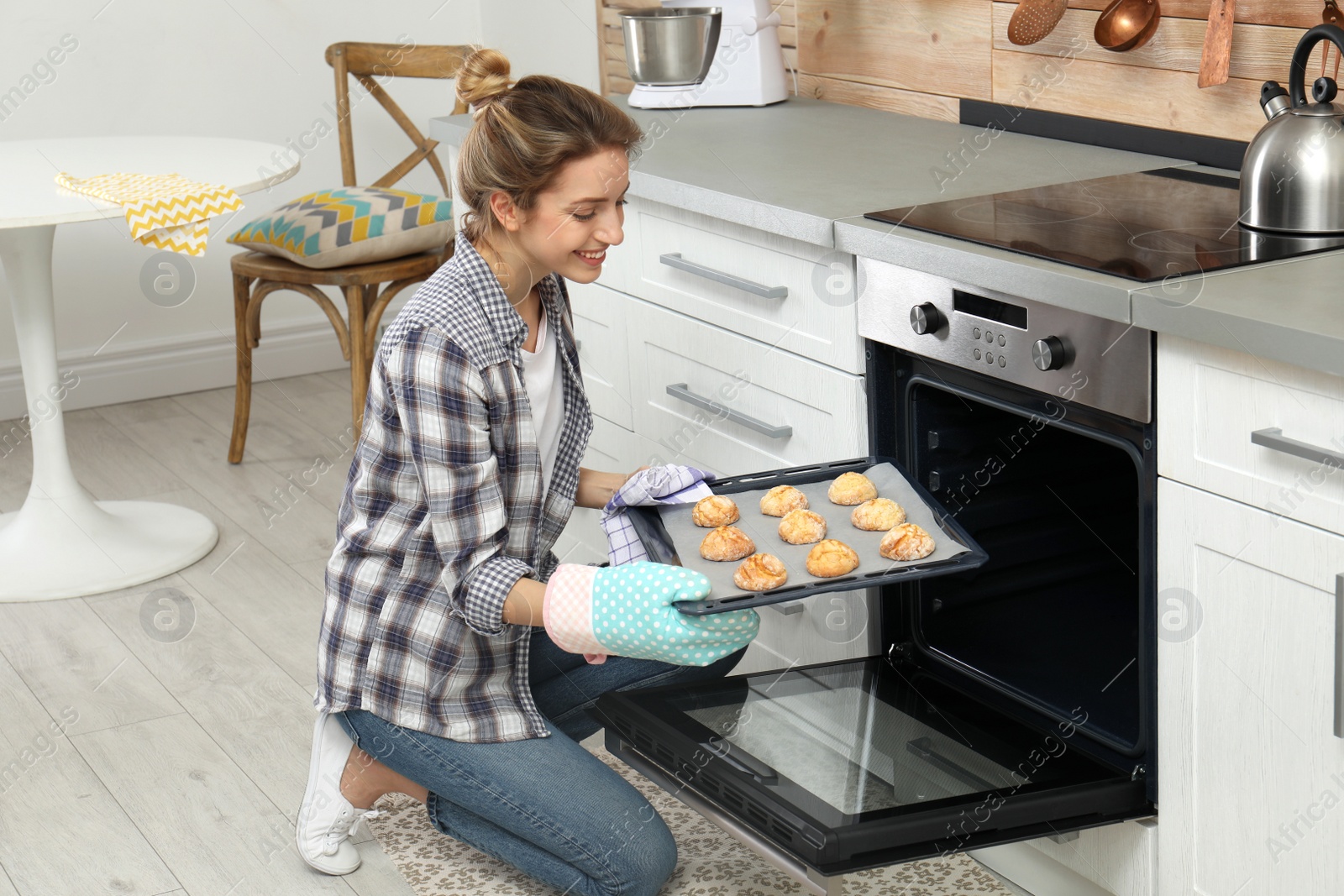 Photo of Young woman baking cookies in oven at home