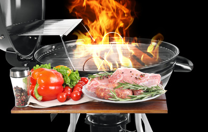 Image of Modern flaming barbecue grill near uncooked food on black background, closeup