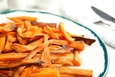 Photo of Plate with baked sweet potato slices on table, closeup