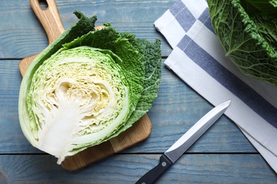 Photo of Cut fresh savoy cabbage on blue wooden table, flat lay