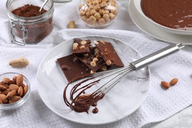 Photo of Whisk with chocolate cream and ingredients on table