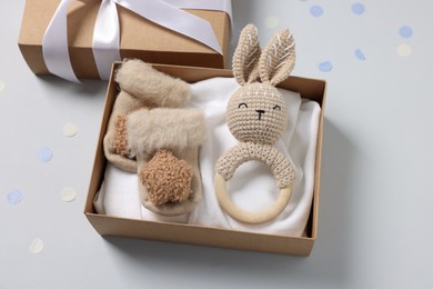 Photo of Different baby accessories in box and confetti on light grey background, above view