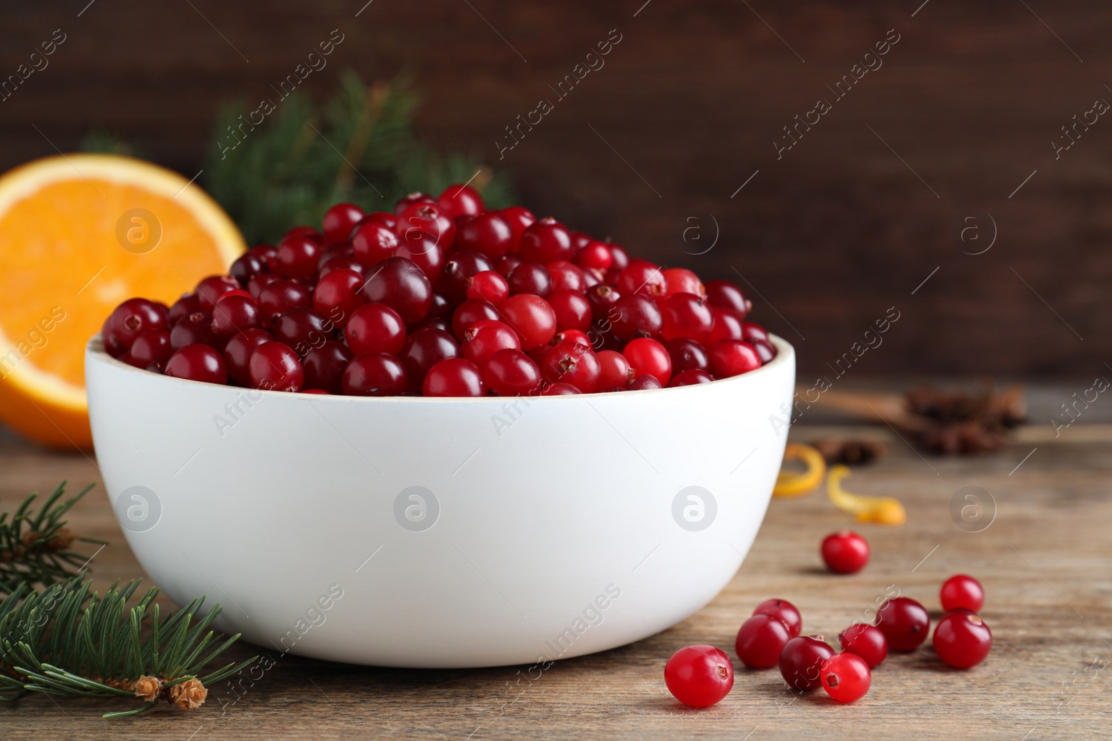 Photo of Fresh ripe cranberries and fir branch on wooden table. Space for text