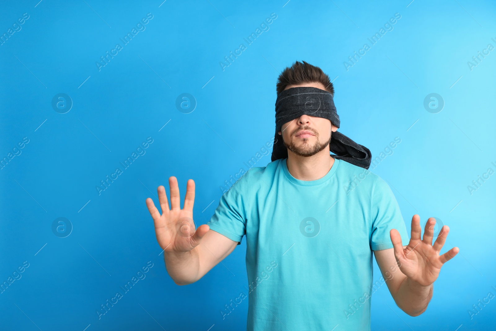 Photo of Man with black blindfold on blue background, space for text