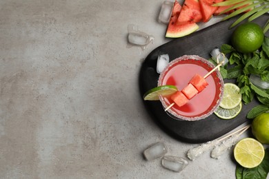 Photo of Cocktail glass of delicious fresh watermelon juice, lime, mint and ice on grey table, flat lay. Space for text