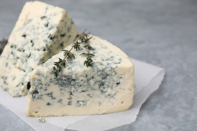 Tasty blue cheese with thyme on grey table, closeup. Space for text