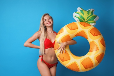 Photo of Pretty young woman wearing stylish bikini with inflatable ring on blue background