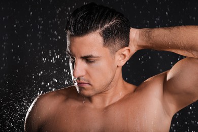Photo of Man washing hair while taking shower on black background