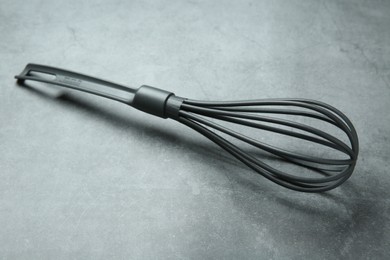Photo of Plastic whisk on gray table. Kitchen tool