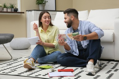 Photo of Happy couple counting money on floor at home