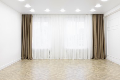 Empty room with white walls, large window and wooden floor