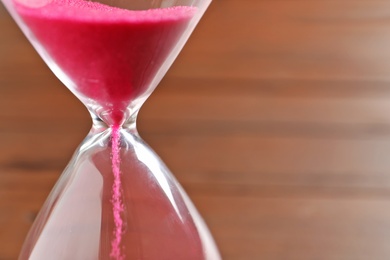 Hourglass with flowing sand on table, closeup. Time management