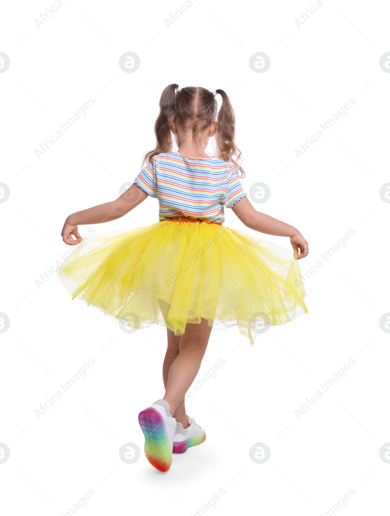 Photo of Cute little girl in tutu skirt dancing on white background, back view