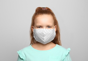 Photo of Preteen girl in protective face mask on light grey background