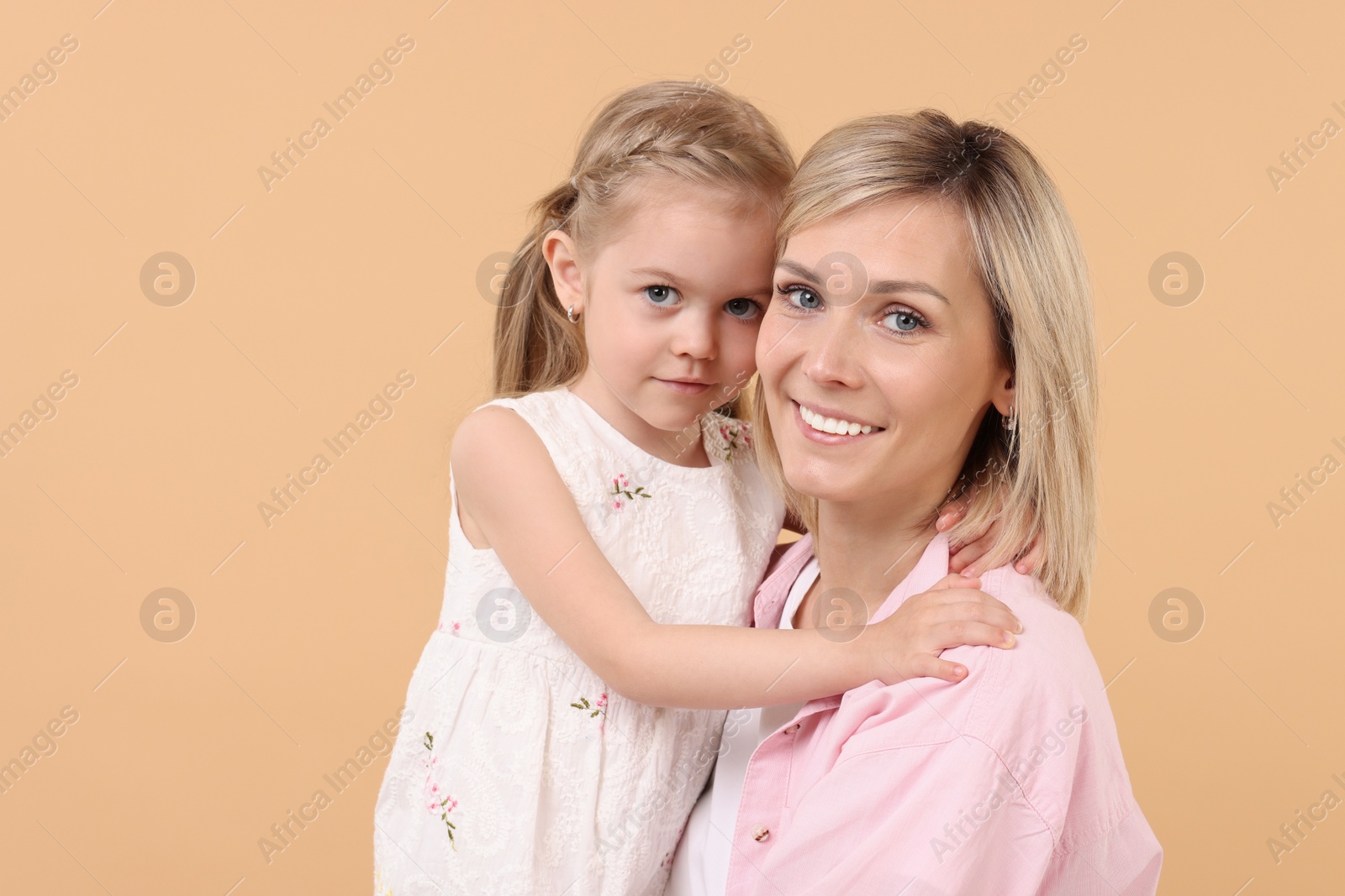 Photo of Family portrait of happy mother and daughter on beige background