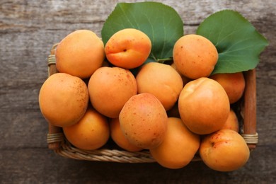 Basket with delicious ripe apricots on wooden table, top view